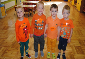 chłopcy ubrani na pomarańczowo stoją w sali